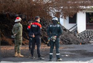 Miembros de la Unidad Militar de Emergencias y de la Policía Canaria observan una de las coladas que atraviesa el barrio de La Laguna, dentro de la zona de exclusión, en foto reciente. EFE/Luis G. Morera