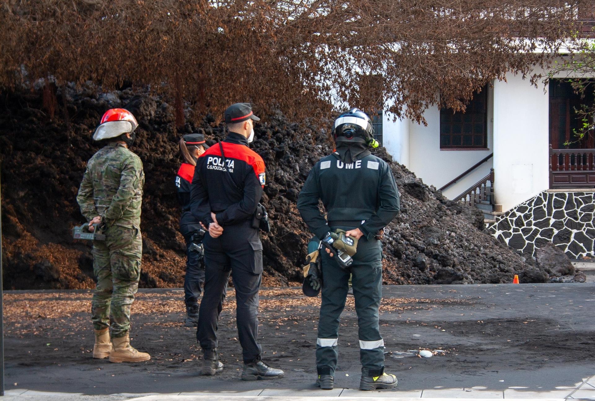 Miembros de la Unidad Militar de Emergencias y de la Policía Canaria observan una de las coladas que atraviesa el barrio de La Laguna, dentro de la zona de exclusión, en foto reciente. EFE/Luis G. Morera