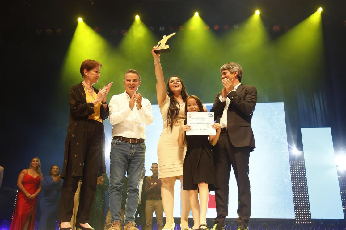 La ganadora del premio Famiempresario Interactuar del año 2022, Dalia Johanna Carrillo Preciado, de la empresa Panadería y Repostería La Reina, celebra hoy junto a su hija, el director ejecutivo de Interactuar, Fabio Andrés Montoya (d), el gobernador de Antioquia, Anibal Gaviria (2-i) y la presidenta de la junta directiva, Beatriz Uribe (i), tras recibir el galardón en Medellín (Colombia).. EFE/Luis Eduardo Noriega A