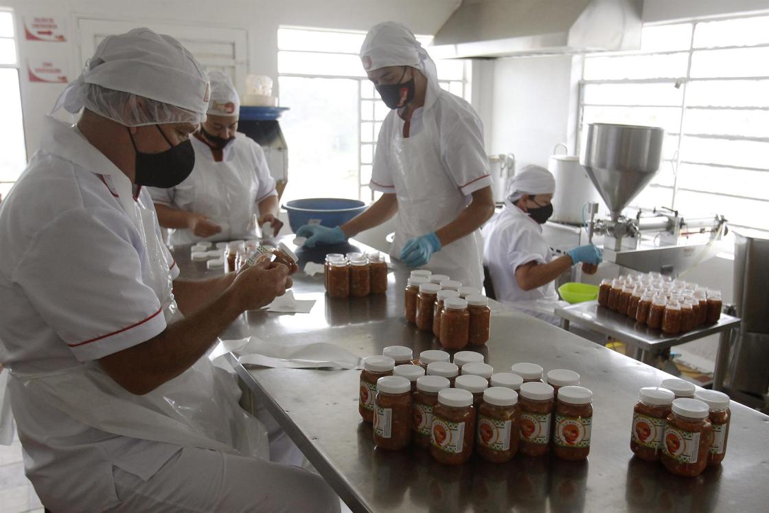 El cofundador de la empresa Aliños en casa, Jorge Iván Parra (i), trabaja junto a empleados en su empresa, el 9 de noviembre de 2022, en Medellín (Colombia). EFE/ Luis Eduardo Noriega A. 