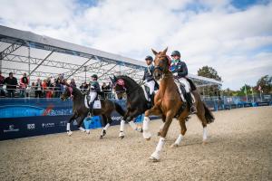 Fotografía cedida por FEI que muestra a Sarah Tubman, Codi Harrison, Anna Marek y Christian Simonson mientras celebran su victoria durante la ceremonia de entrega de medallas de doma clásica por equipos en los Juegos Panamericanos 2023. EFE/ Cortesía FEI