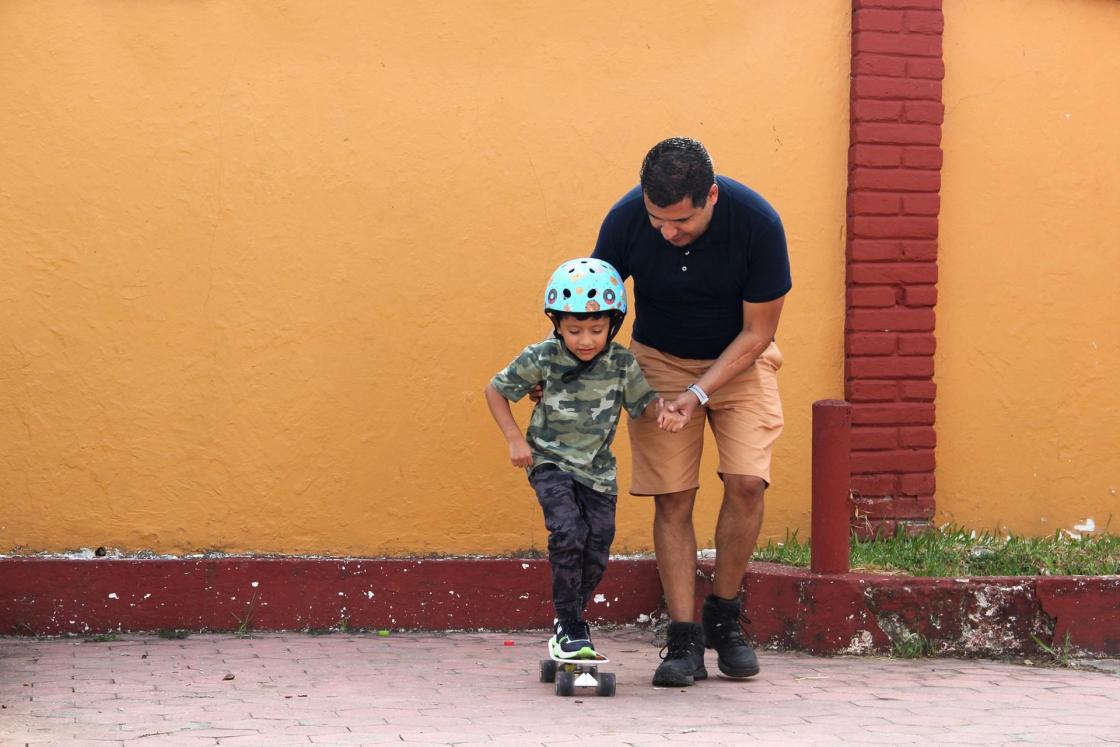Papá soltero latino le enseña a su hijo a andar en patineta con casco muy divertido y feliz del logro de aprender algo nuevo. SOLO USO EDITORIAL /Shutterstock /EFE 