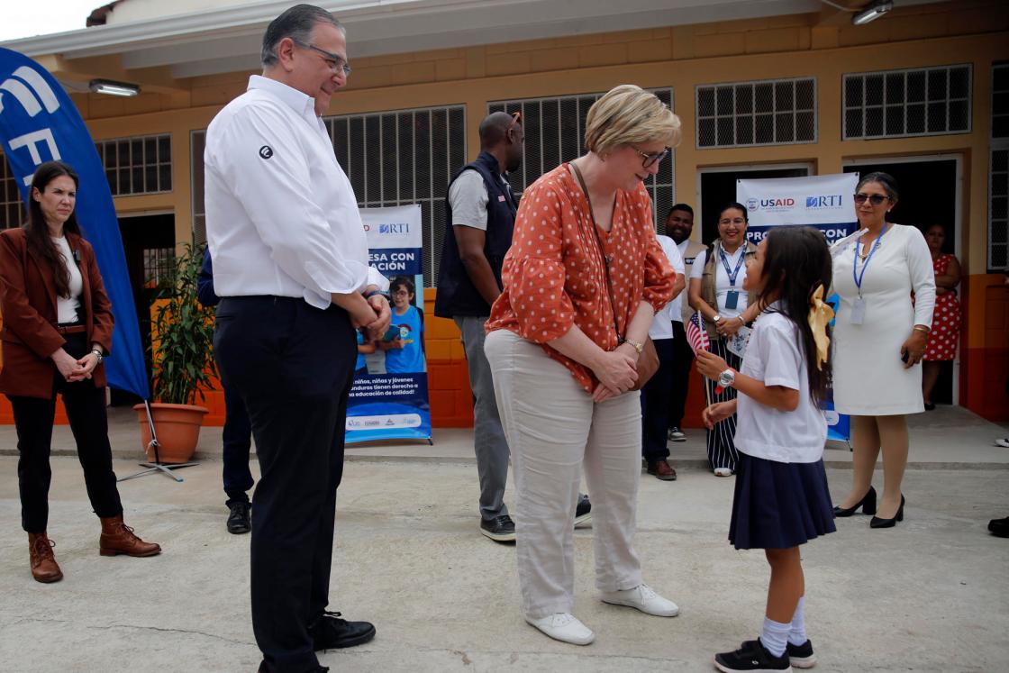 La embajadora de Estados Unidos en Honduras, Laura Dogu (c), saluda a una estudiante junto a Luis Átala (i), vicepresidente de Grupo Ficohsa (d), durante un evento en el Centro de Educación Básica Armando Montes en Juticalpa (Honduras). EFE/ Gustavo Amador 