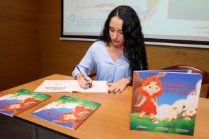 GRAFCAN9473. LAS PALMAS DE GRAN CANARIA, 18/12/2024.- La colección Cuentos Solidarios suma su decimotercer título, 'Cuidado con lo que deseas', que reflexiona sobre la infancia y la gestión de las tecnologías y cuya recaudación irá destinada a la Asociación Canaria Sociosanitaria Te Acompañamos. Ariadna Santana Fiérrez, autora del cuento ganador del concurso 'Cuentos Solidarios', un proyecto sociocultural promovido por la Fundación Mapfre Canarias, ha explicado en rueda de prensa que el libro narra la historia de Athenea, una niña de diez años que desea recibir por su cumpleaños su primer teléfono móvil, como el que ya tiene el resto de los compañeros de clase, porque considera que ya es una niña mayor.En la imagen, la autora del cuento Ariadna Santana firma su libro durante la presentación del cuento. EFE/ Elvira Urquijo A.
