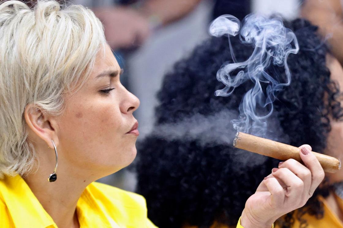 HAVANA (CUBA), 02/26/2025.- A woman smokes a cigar during the cigar rolling competition in Havana (Cuba). As part of the 25th edition of the Festival del Habano, organized by the Spanish-Cuban tobacco company Habanos, the traditional cigar rolling competition was held, featuring artisans who handcraft Cuba’s most prized cigars using traditional techniques. EFE/Ernesto Mastrascusa.