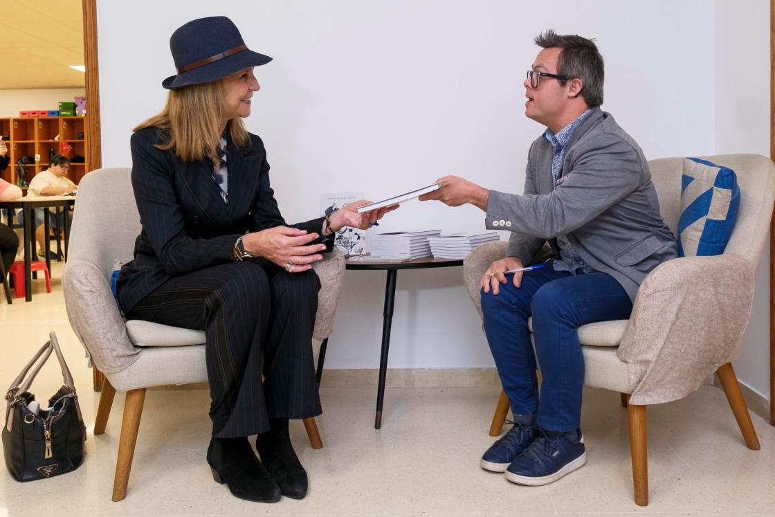 GRAFCAN7922. LAS PALMAS DE GRAN CANARIA (ESPAÑA), 11/12/2025.- La infanta Elena (i) visitó los proyectos de integración social y laboral que la Fundación Mapfre Canarias impulsa en Gran Canaria en colaboración con la Asociación Down Las Palmas. En la imagen, el escritor y usuario del centro Héctor Santana (d) entrega a la hermana del rey un ejemplar de su libro 'Mi vida no es un cuento'. EFE/Ángel Medina G.