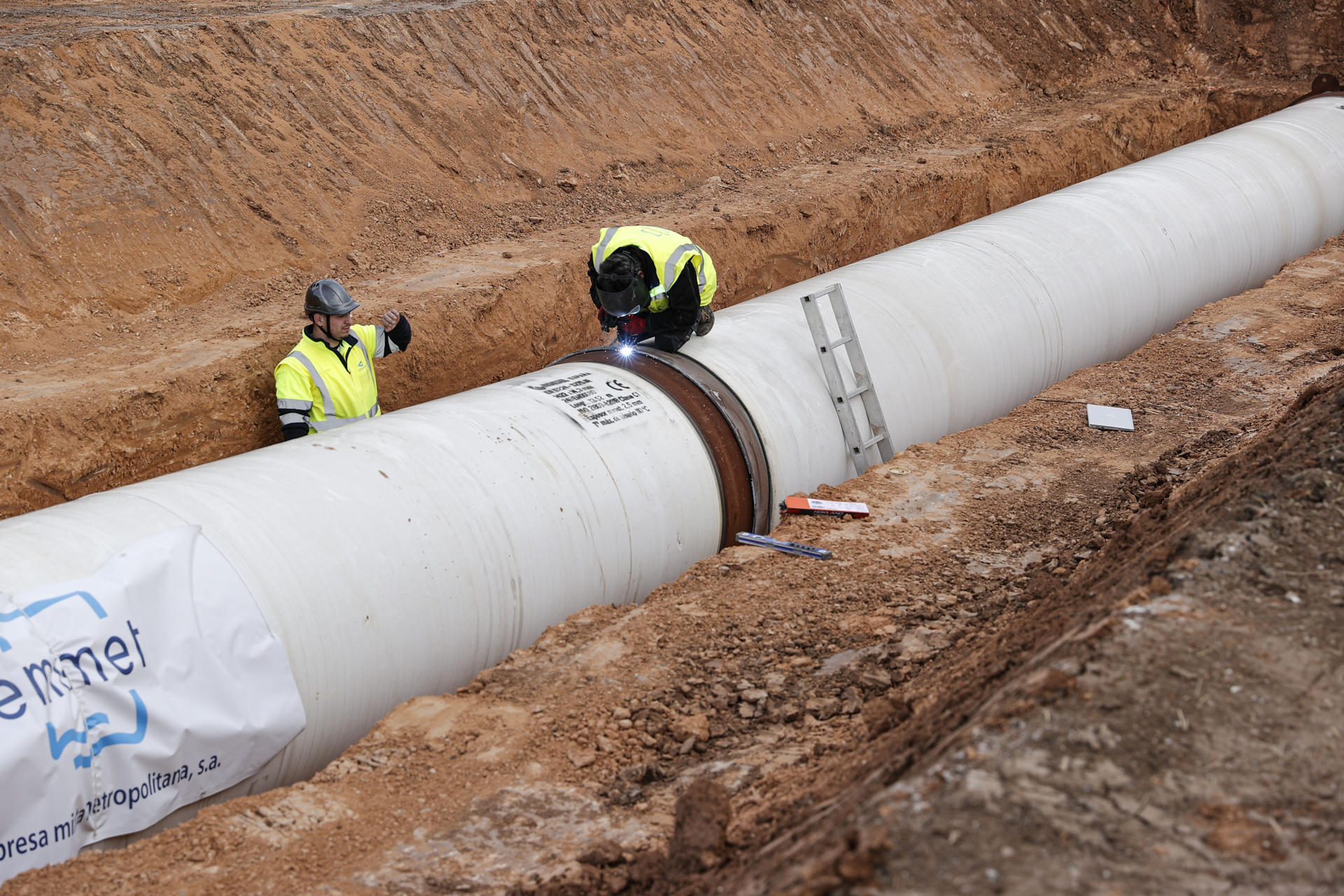 La alcaldesa de València, María José Catalá, y la Entidad Metropolitana de Servicios Hidráulicos (Emshi) visitan las obras correspondientes al último tramo que permitirán la interconexión entre las dos Plantas Potabilizadoras de La Presa (Manises) con la de El Realón en Picassent, una infraestructura estratégica para reforzar la garantía de suministro de agua potable en el conjunto de municipios del área metropolitana y de la ciudad de València, que ha supuesto una inversión de 13 millones de euros. En la imagen varios operarios trabajan en la colocación de una nueva canalización. EFE/Manuel Bruque